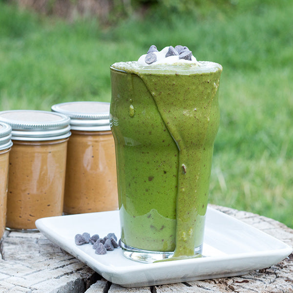 Coconut Peanut Butter Shamrock Shake with coconut peanut butter jars in background