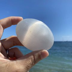 Person holding Selenite Palm Stone at the beach
