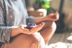 Person meditating with purple healing crystal