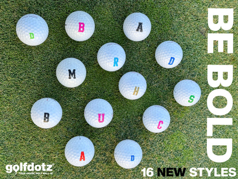 Golf balls with large colored lettering on green