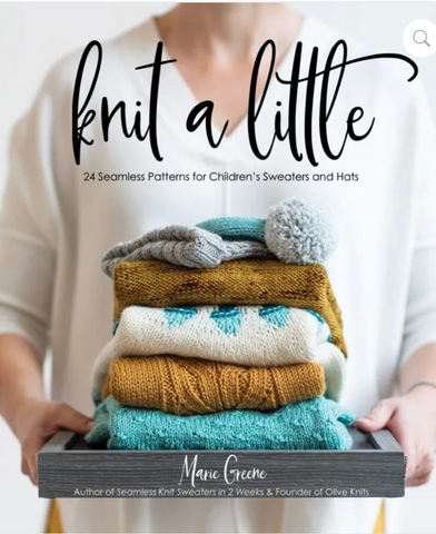 photo of a book titled Knit a Little. woman wearing a white sweater and holding a stack of tiny knitted sweaters in cream, turquoise, and gold.