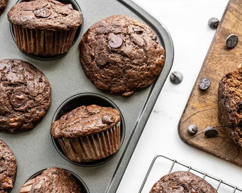 a tray of chocolate muffins sits on a white surface