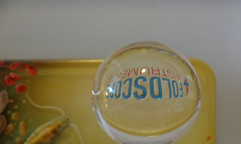 Lens ball in front of Foldscope Deluxe Kit Tin