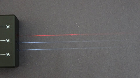 Light box producing  one red and two white parallel lines of light over a black surface