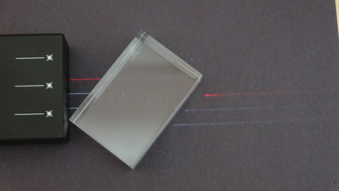 Light box producing  one red and two white parallel lines of light hitting an acrylic block and refracting