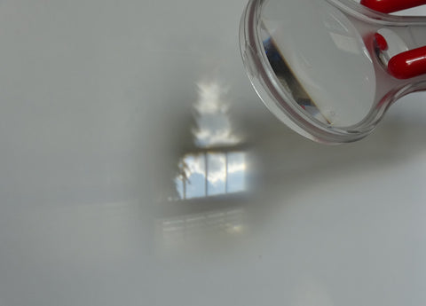 A hand lens producing a small upside down image on a white background