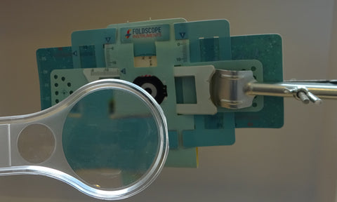 A hand lens in front of a Foldscope