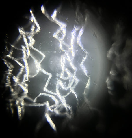 Picture of a fake spiderweb viewed under a Foldscope 2.0 at 50X magnification using dark field lighting