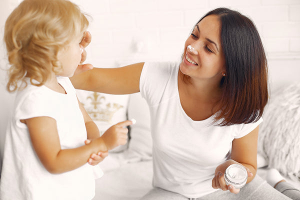 mother putting moisturizer on child with eczema