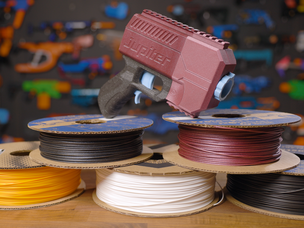 The Out of Darts Jupiter blaster on top of stacked cardboard spools from Proto-Pasta