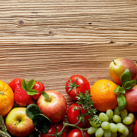 Fruits and vegetables across a wood background.