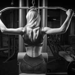 Image of a woman in athletic apparel working out her back on a fitness machine.