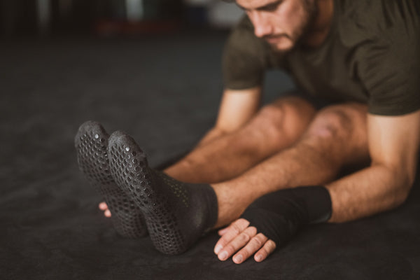 Man stretching wearing Base 33 Black Grip Socks