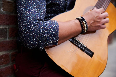 Close up on man's right arm as he plays wood guitar and shows sleeve cuffed using FLXCUF