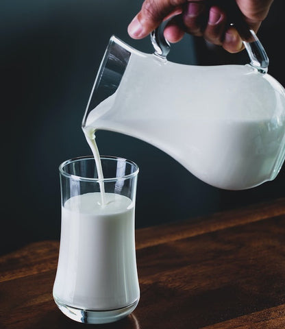 person pours milk into glass