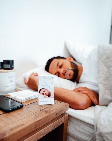 A man uses SomniFix mouth tape to prevent snoring and promote nasal breathing for quality sleep.