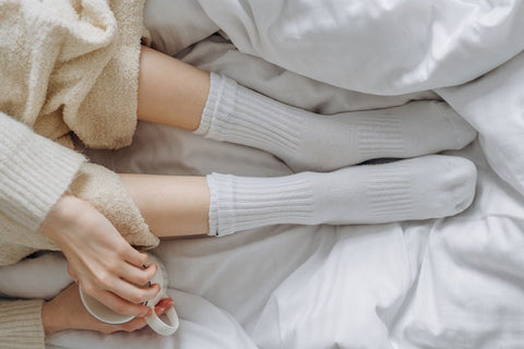 A woman lays in bed with socks on.