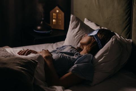 A woman sleeps with a blue silk eye mask on.