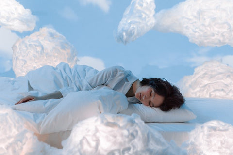 A woman lays among the clouds in a dream-like setting.