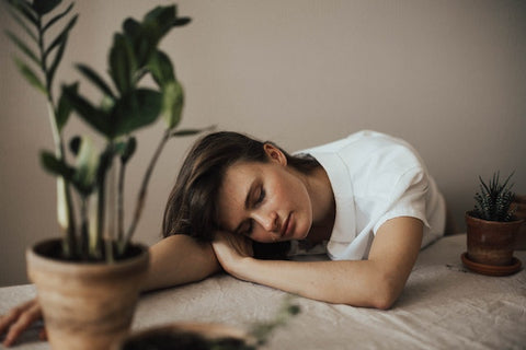 Woman wearing collared top sleeps on table.