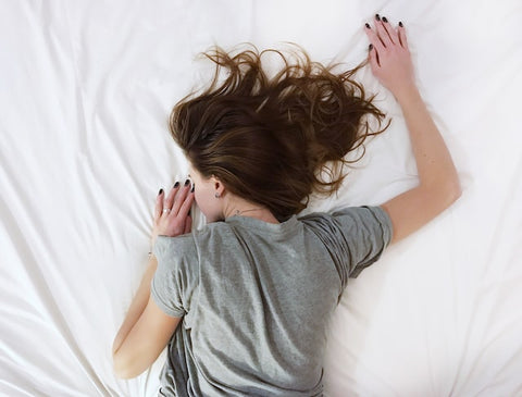 Woman laying in bed with white sheets.