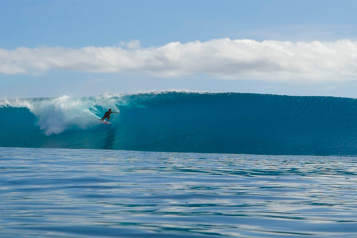 logan nicol taking a high line through the barrel on a big left hander in the mentawai islands