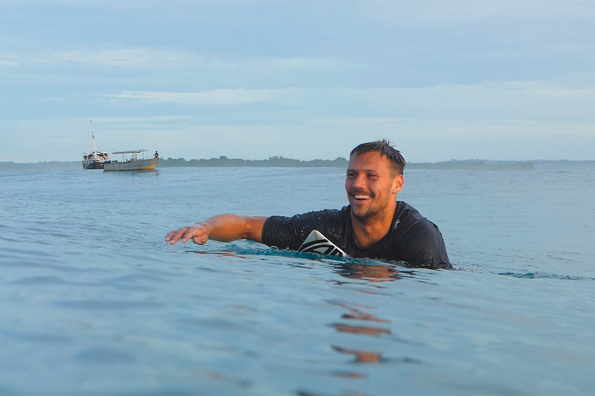 surfer logan nicol paddling back out after a perfect wave in the mentawai islands in indonesia