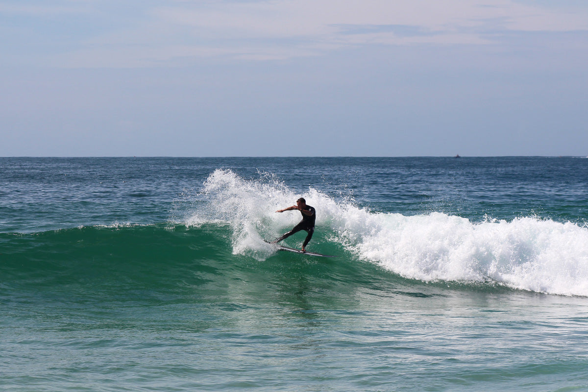 a surfer in a short sleeve wetsuit makes a big turn