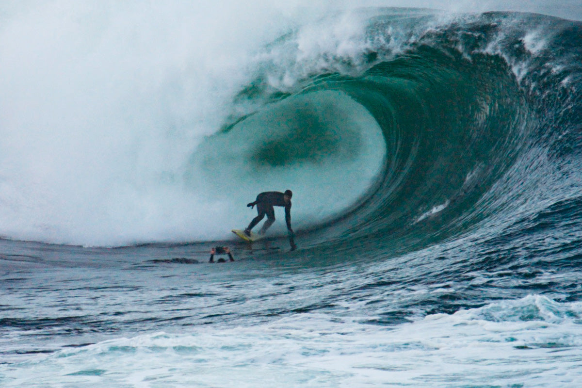 irish surfer surfer ollie o'flaherty dropping into a big wave in front of photographers at riley's surf spot