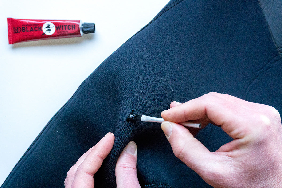 using black witch neoprene adhesive to repair a hole in a wetsuit