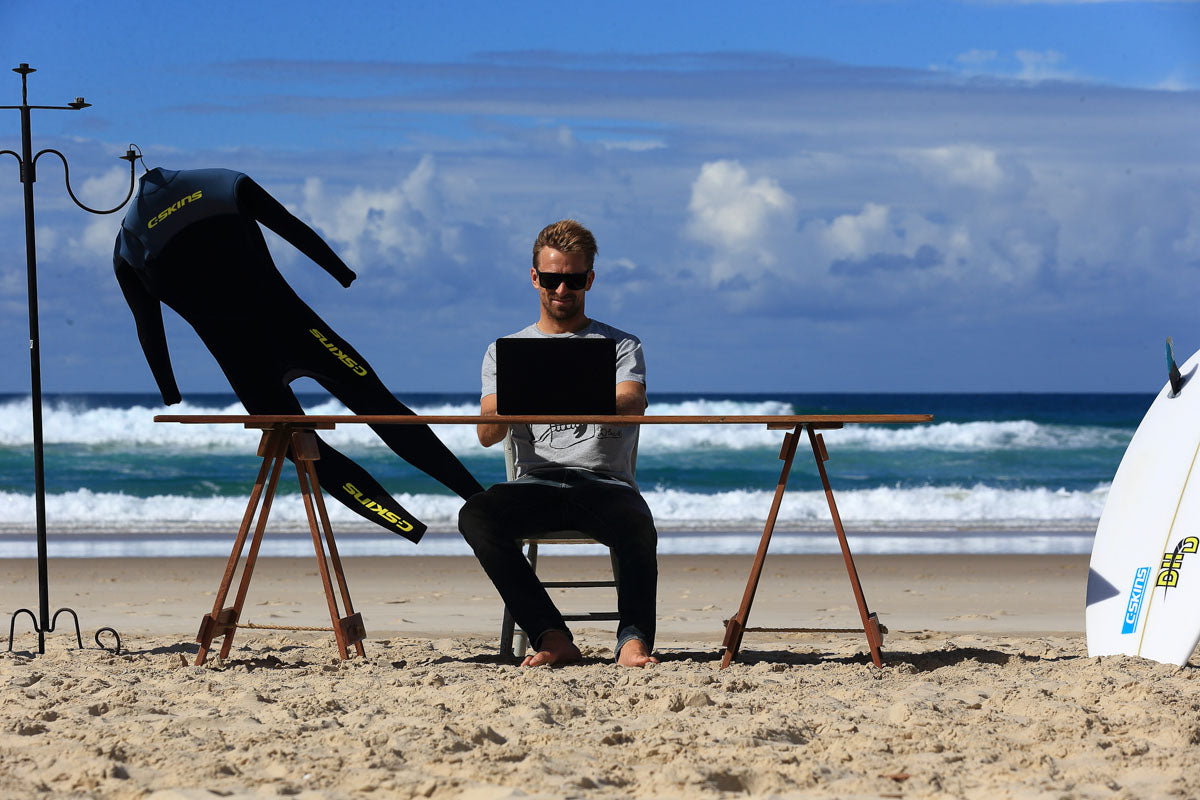 Kieren perrow sitting on a desk on the beach