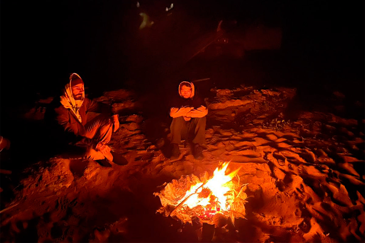 surfers edouard delpero and damien castera sat around a camp fire in mexico