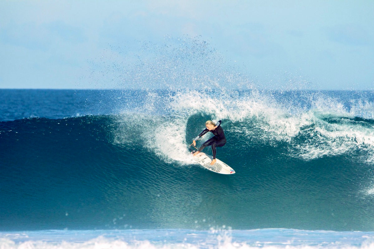 Sophie surfing big waves in a wetsuit