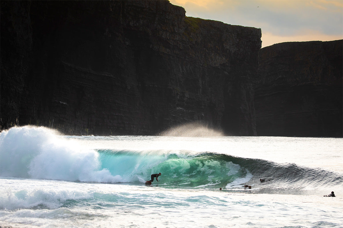 ollie getting barrelled in Ireland with the cliffs in the background 