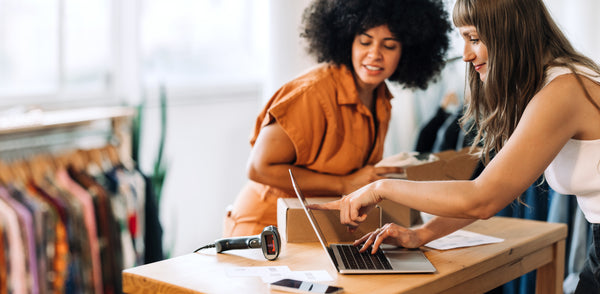 two woman looking at a laptop screen in an office