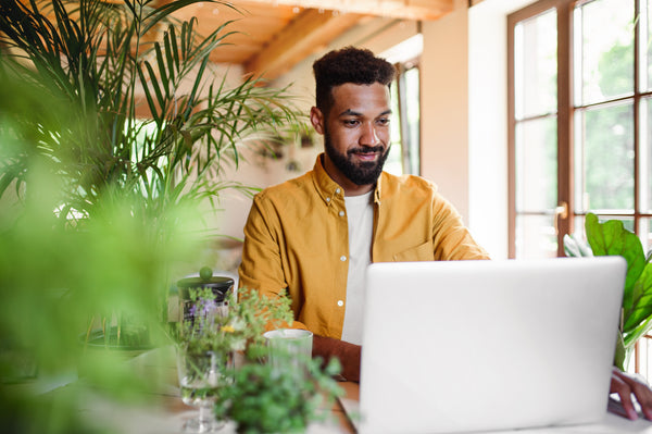 man sitting at his laptop behind a plant