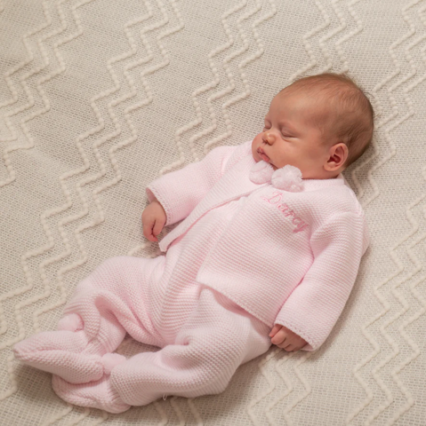 baby wearing pink sleepsuit
