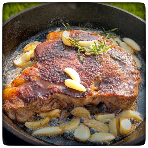 A cooked seak in a cast iron skillet with garlic and rosemary