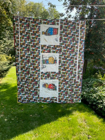 Jellybean Quilt shown from the back featuring three corners of Prescott and Gower Streets in St. John's against a background of a fabric showing the colourful houses of the city in bright colours against a white background.