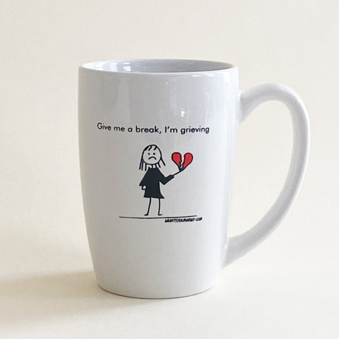 A mug with a stick figure holding a broken heart. Text reads, "Give me a break. I'm grieving."
