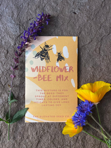 Package of wildflower seeds with yellow, blue, and purpose flowers surrounding the package