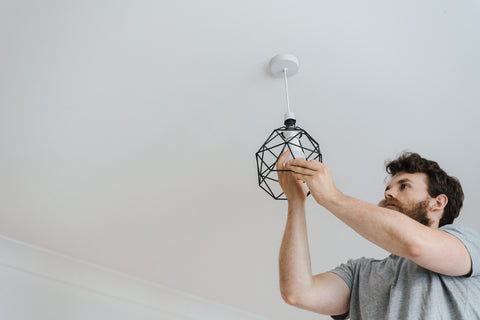 Man changing a lightbulb in a ceiling light fixture