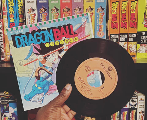 Popular 80s anime Dragon Ball Single Album held in front of a bookshelf with Dragon Ball merchandise