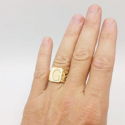initial signet ring on the ring finger of the left hand