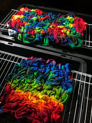 Yards of fleece fabric being tie dyed in a rainbow splatter design