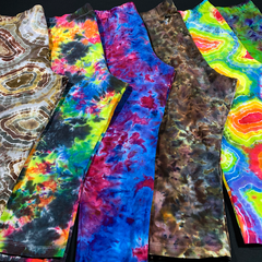 A special order for 10 pairs of custom tie dye leggings, each in a different color combo and pattern, all laid flat against one another, on a solid black background