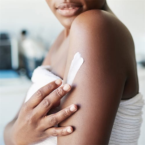 a photo of a person rubbing lotion into their left shoulder