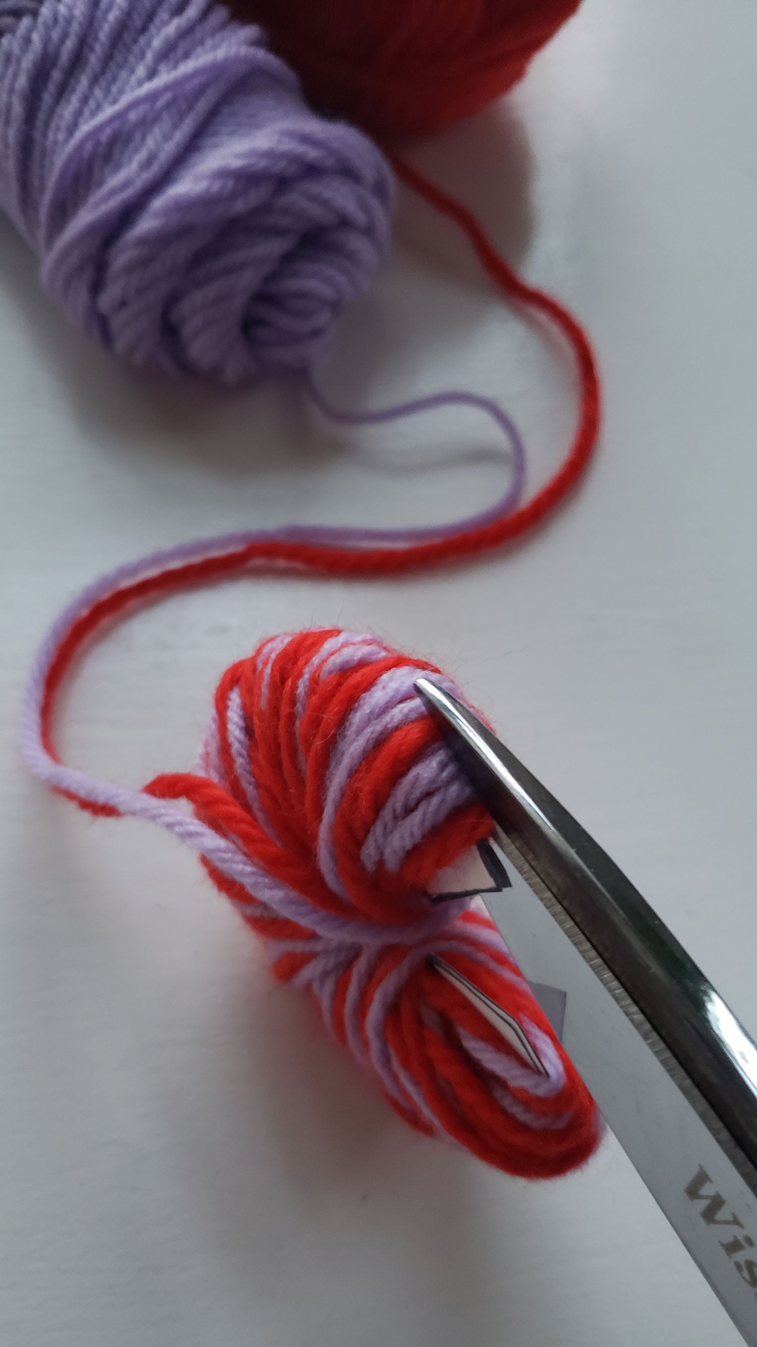 yarns being cut along the edge of the pom pom maker