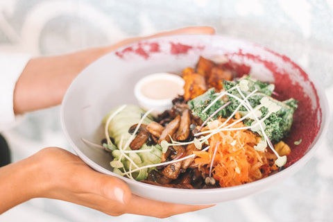 Person holding bowl of vegan meal