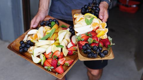 Person carrying trays of fruits